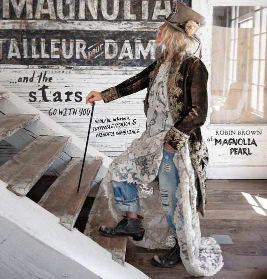 Magnolia Pearl artisan clothing model in whimsical vintage outfit on rustic staircase
