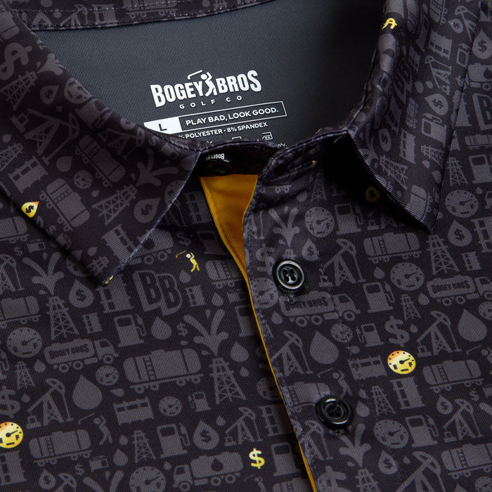 Close-up of the Gusher - Polo, a dark gray collared shirt with a golf-themed print featuring oil rigs, dollar signs, golf balls, and water drops. It offers an athletic fit, UPF 50 protection, black buttons, and a yellow accent inside the placket.
