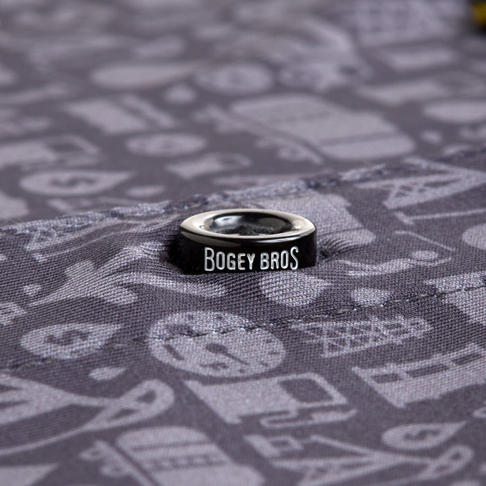 The Gusher - Polo features a black metal eyelet with BOGEY BROS in white, set into gray, moisture-wicking fabric patterned with blurred golf-themed icons for a stylish and dry wear.