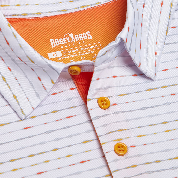 A close-up of the Heat Index - Polo, a white athletic-fit shirt with thin gray, orange, and yellow wavy stripes, bright orange buttons, an orange inner collar, and moisture-wicking fabric to keep you cool and dry.