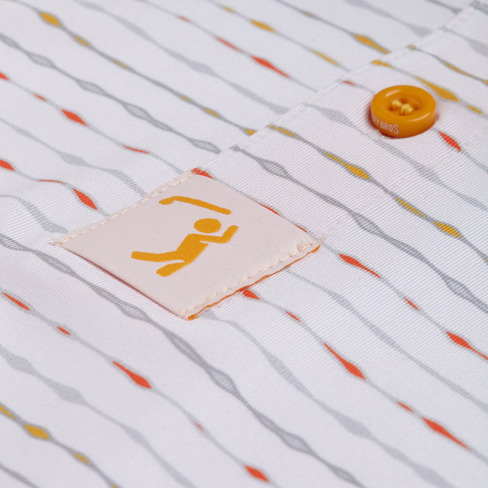 A close-up of the Heat Index - Polo’s white fabric with wavy orange, gray, and yellow lines, orange button, and patch showing an orange stick figure. This athletic fit polo offers visible stitching and UPF 50 protection.