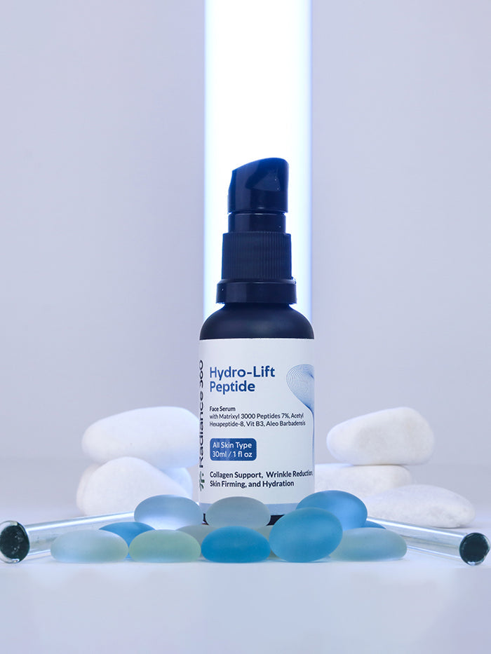 Hydro-Lift Peptide skincare bottle with pebbles and blue glass beads on a light gray background