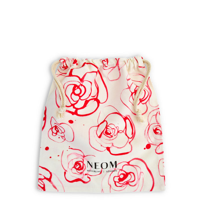Drawstring bag with red floral patterns and NEOM branding on a white background