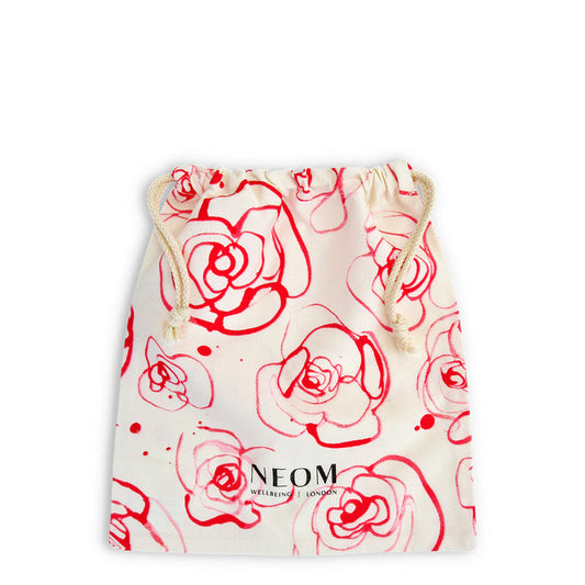 Drawstring bag with red floral patterns and NEOM branding on a white background