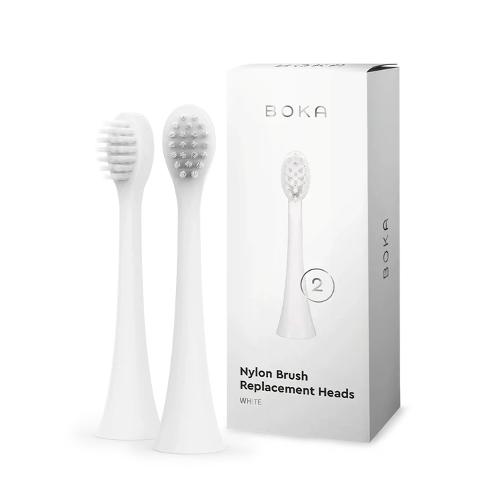 Two kids sonic toothbrush replacement heads stand beside a Boka replacement heads box.