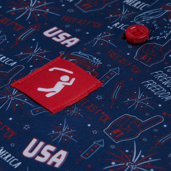 Close-up of the 'Merica - Navy - Polo, an athletic fit shirt with red and white Fourth of July graphics—fireworks, USA, foam finger, Free as F*ck, raised fist—plus UPF 50 protection, a red Bogey Boys button, and moisture-wicking fabric.