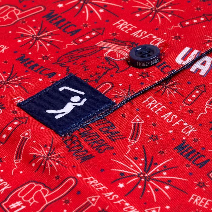 Close-up of the 'Merica - Red - Polo featuring white and blue fireworks, a foam finger, stars, “FREE AS F*CK,” and “MERICA.” Includes moisture-wicking fabric, navy Bogey Bros button, athletic fit, and pocket tag with golfer.