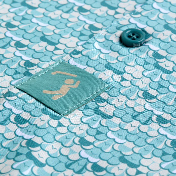 A close-up of the T&A - Luscious - Polo in teal shows its blue fish scale pattern and athletic fit with UPF 50. A small teal label and a BODETT-embossed button offer distinctive touches.