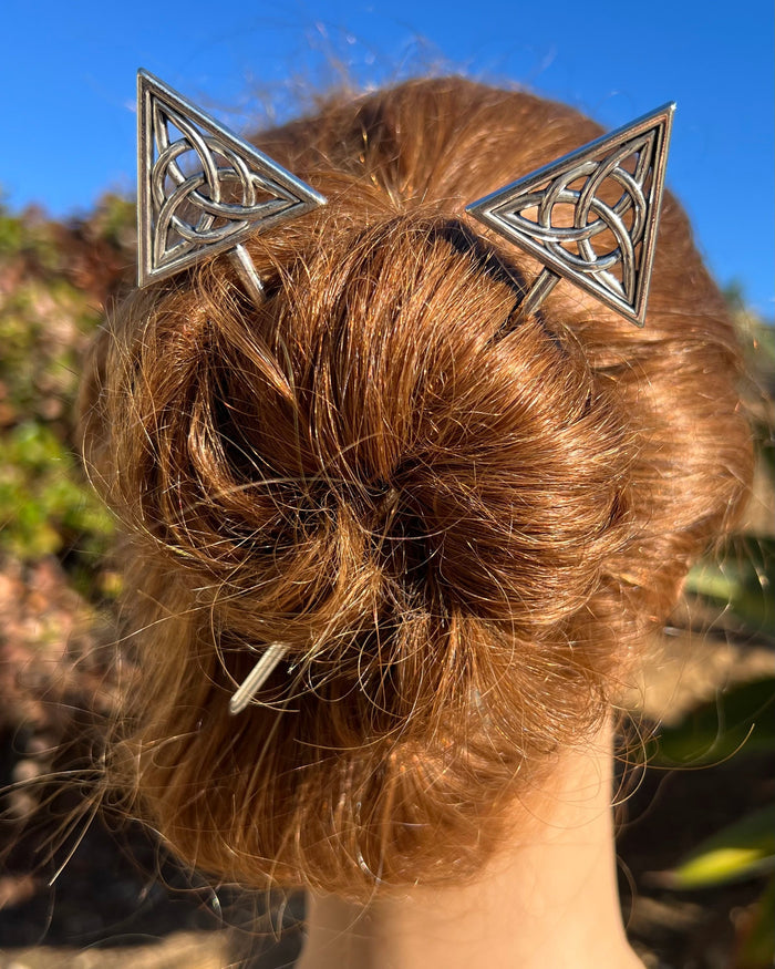 Model wearing Unity Hair Sticks with silver Celtic knot triangle design securing a bun hairstyle, decorative metal hair pins for elegant updos and everyday wear.