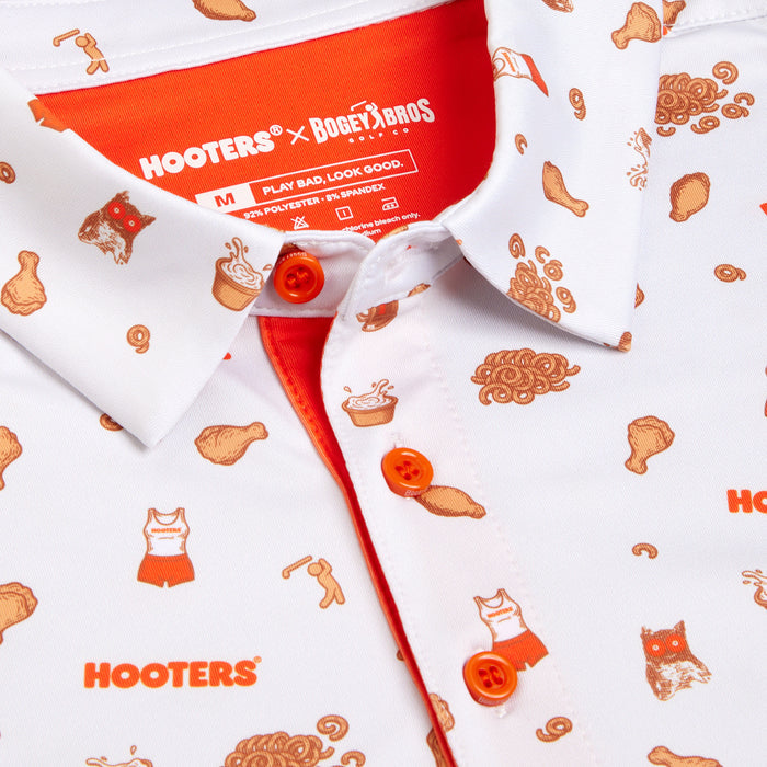 Close-up of the Wingin' It - White - Polo, featuring an orange Hooters x BOGEY BROS logo, playful cartoon patterns, orange buttons, inner placket lining, and UPF 50 protection in an athletic fit.